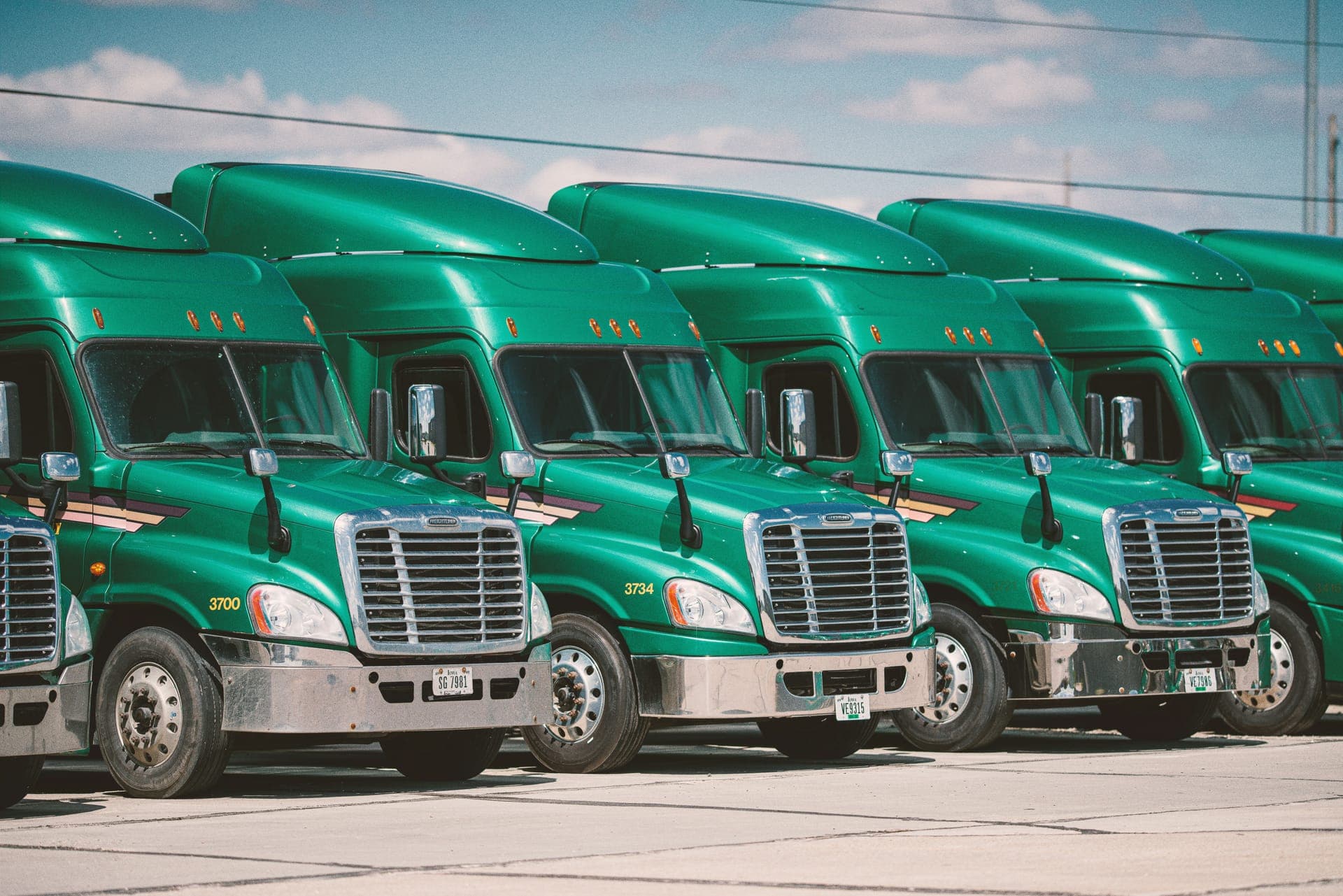 Row of green semi-trucks parked in a US fleet yard