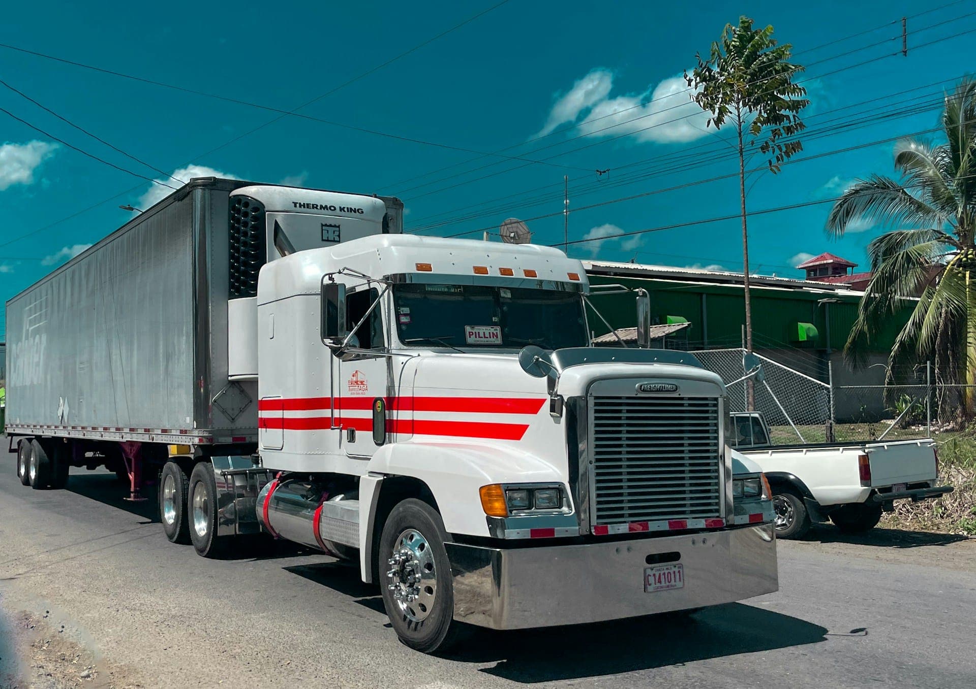 White semi-truck with a refrigerated trailer parked by the road
