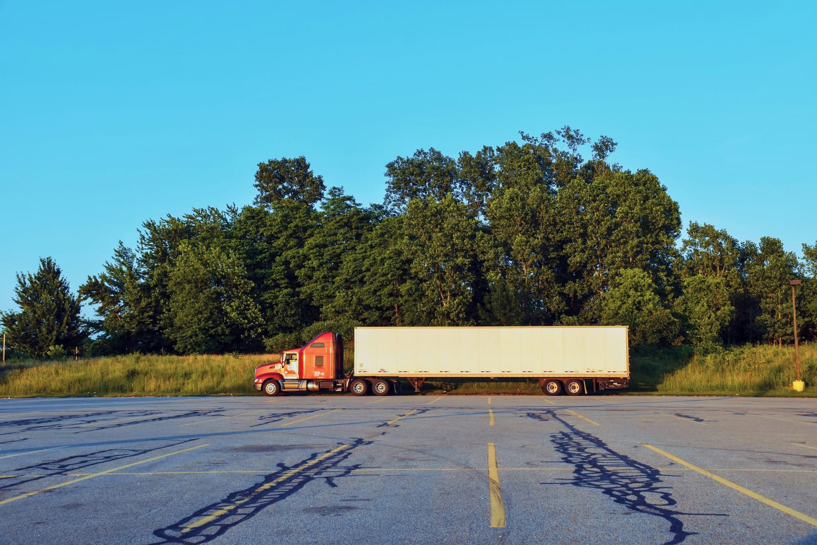 Red day cab semi-truck parked at a US lot
