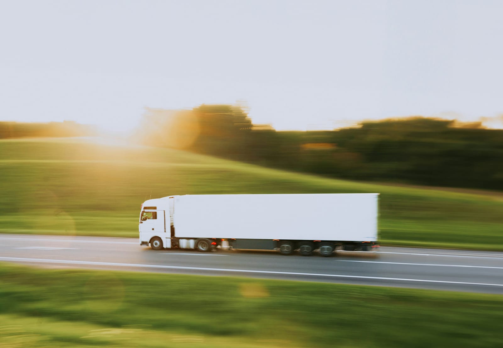 White semi-truck moving along a country highway